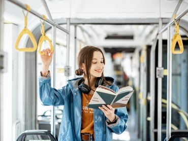 Young woman reading book while standing in the modern tram, happy passenger moving by comfortable public transport, Image: 433660659, License: Royalty-free, Restrictions: , Model Release: yes, Credit line: Profimedia, Alamy